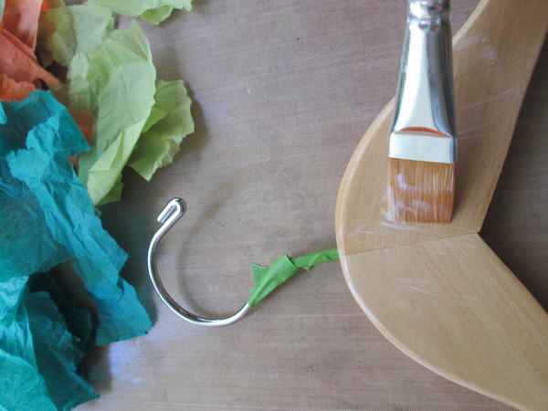 Brush a thin coat of decoupage medium onto the large center section of the hanger. Brush a thin coat of decoupage medium onto the large center section of the hanger.